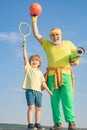 Grandfather and grandson with basketball ball and yoga mat in hands. Father and son having workout. Age is no excuse to Royalty Free Stock Photo