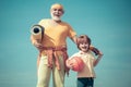 Grandfather and grandson with basketball ball and yoga mat in hands. Senior man and cute little boy exercising on blue Royalty Free Stock Photo