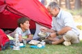 Grandfather And Grandson Cooking Breakfast On Camping Holiday