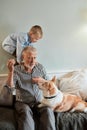 Grandfather and grandson with dog sitting at couch in room Royalty Free Stock Photo