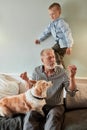 Grandfather and grandson with dog sitting at couch in room Royalty Free Stock Photo