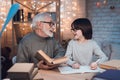 Grandfather and grandson are doing homework at night at home. Granddad is helping boy. Royalty Free Stock Photo