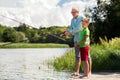 Grandfather and grandson fishing on river berth