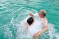 Grandfather and grandson get hydromassage in warm thermal pool