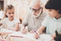 Grandfather, grandson and granddaughter at home. Children are drawing with color pencils. Royalty Free Stock Photo