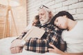 Grandfather, grandson and granddaughter at home. Grandpa and children are sleeping while reading book. Royalty Free Stock Photo