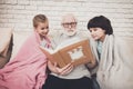 Grandfather, grandson and granddaughter at home. Grandpa and children are watching photos in album. Royalty Free Stock Photo