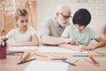 Grandfather, grandson and granddaughter at home. Children are drawing. Royalty Free Stock Photo