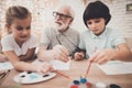 Grandfather, grandson and granddaughter at home. Children are painting. Royalty Free Stock Photo