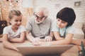 Grandfather, grandson and granddaughter at home. Grandpa and children are using laptop.