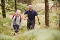 Grandfather and grandson hiking in a forest amongst greenery, selective focus