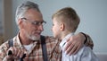 Grandfather and grandson looking each other in eyes, two generations, closeup