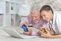 Portrait of grandfather and grandson lying on floor and playing computer games on laptop Royalty Free Stock Photo