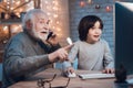 Grandfather and grandson are playing games on computer at night at home. Granddad is cheering for boy. Royalty Free Stock Photo
