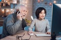 Grandfather and grandson are playing games on computer at night at home. Granddad is on phone. Royalty Free Stock Photo