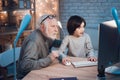 Grandfather and grandson are playing games on computer at night at home. Granddad is cheering for boy. Royalty Free Stock Photo