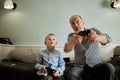 Grandfather and grandson playing video games on computer with joystick Royalty Free Stock Photo