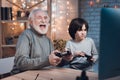 Grandfather and grandson are playing video games on computer at night at home. Royalty Free Stock Photo