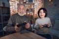 Grandfather and grandson are playing video games at night at home. Royalty Free Stock Photo