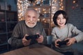 Grandfather and grandson are playing video games at night at home. Royalty Free Stock Photo