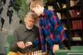 Grandfather and grandson are setting wooden chess figures on chessboard preparing to play.