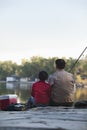 Grandfather and grandson sitting and fishing at a lake