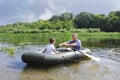 Grandfather with grandson swim in a rubber boat on the river.