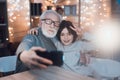 Grandfather and grandson are taking selfie on phone at night at home. Royalty Free Stock Photo