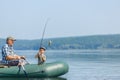 grandfather with grandson together fishing from inflatable boat Royalty Free Stock Photo