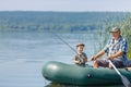 grandfather with grandson together fishing from inflatable boat Royalty Free Stock Photo