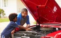 Grandfather And Grandson Working On Restored Classic Car