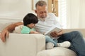 Happy grandfather with his grandson reading book together at home Royalty Free Stock Photo