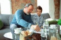 Grandfather and his grandson spending time insulated at home, stadying, writing, drawing or playing together