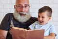 Grandfather and his grandson spending time together reading a fu Royalty Free Stock Photo