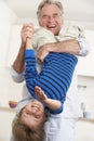 Grandfather Holding Grandson Upside Down At Home