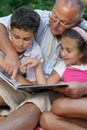 Grandfather and kids reading book Royalty Free Stock Photo