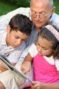 Grandfather and kids reading book Royalty Free Stock Photo