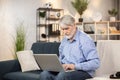 Grandfather looking through kids' photos on computer indoors