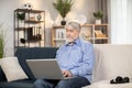 Grandfather looking through kids' photos on computer indoors