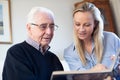 Grandfather Looking At Photo Album With Adult Granddaughter