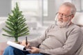 Grandfather making the shopping list for winter holidays Royalty Free Stock Photo