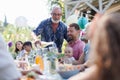 Grandfather opening bottle of champagne, pouring wine into glasses. Senior man making celebratory toast at outdoor Royalty Free Stock Photo