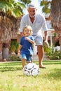 Grandfather Playing Football With Grandson In Garden