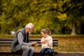 Grandfather playing red hands slapping game with his granddaughter in park on autumn day Royalty Free Stock Photo