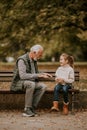 Grandfather playing red hands slapping game with his granddaughter in park on autumn day Royalty Free Stock Photo