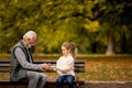 Grandfather playing red hands slapping game with his granddaughter in park on autumn day Royalty Free Stock Photo