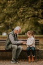 Grandfather playing red hands slapping game with his granddaughter in park on autumn day Royalty Free Stock Photo