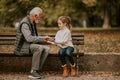 Grandfather playing red hands slapping game with his granddaughter in park on autumn day Royalty Free Stock Photo