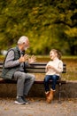 Grandfather playing red hands slapping game with his granddaughter in park on autumn day Royalty Free Stock Photo