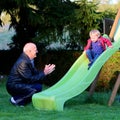 Grandfather plays with granddaughter on playground Royalty Free Stock Photo